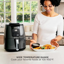 Black air fryer on countertop with person serving food from the basket