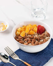 White ceramic dipping bowl with beans and fruit, on a blue napkin
