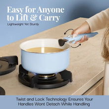 Light blue ceramic pot on gas stove with detachable handle being twisted on