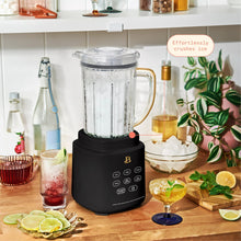 Black countertop blender with clear pitcher blending and ingredient bottles around it