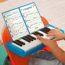 Mini musician's piano toy with open songbook and a child playing the keys