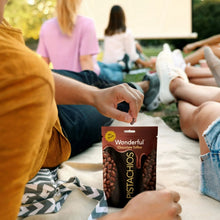 Chocolate toffee pouch with pistachios held in hands on a blanket