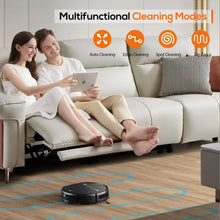 Black robot vacuum on living room floor near a sofa and cushions