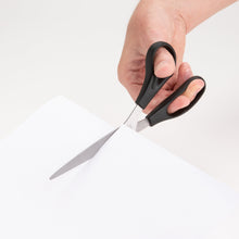 Stainless steel scissors with black handles cutting through paper