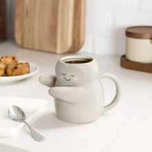 Sculpted hug earthenware mug with closed-eye face, curved arm handle, white-gray
