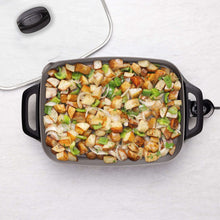 Electric ceramic skillet, open pan with roasted vegetables and scattered herbs