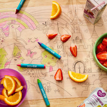 Black-and-white coloring placemat with crayons and scattered fruit on table