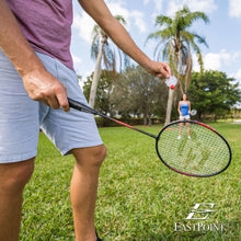 Badminton racket held outdoors with green and red shuttlecock near the strings