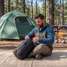 Double sleeping bag, rolled and secured in a dark fabric carry bundle