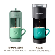 Two Keurig pod coffee makers, Glamping Green and dark gray, each with mug under spout