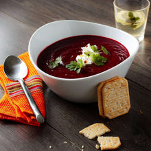White wavy porcelain soup bowl with red contents and herb garnish