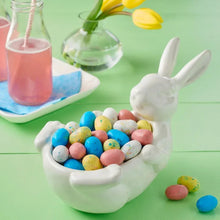 Hand holding a white bowl filled with multicolor speckled egg candies