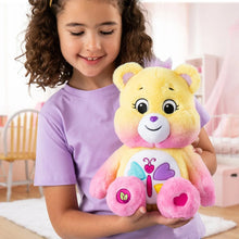 Plush calming heart bear held in a child’s arms, yellow face and pink paws