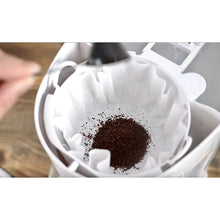 Brewing chamber with paper filter holding dark coffee grounds