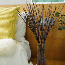 Unlit black willow-style branches in a clear vase for display