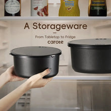 Black storage cookware pots with tight-fitting lids, held by two hands