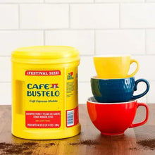 Ground espresso coffee canister beside three colorful mugs on a tabletop