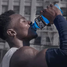 Athlete sipping from a blue Powerade sports drink bottle held near mouth.