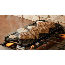 Reversible cast iron griddle on burner cooking steak with sliced onions