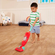 Toy vacuum cleaner with red handheld and teal nozzle on wooden floor