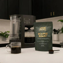 Eclipse Roast dark roast ground coffee bag beside coffee maker and cup
