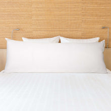 White body pillow in front view on a bed with a textured fabric wall background.