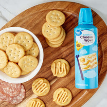 Cheese spray bottle with blue cap beside round crackers with cheese drizzle design.
