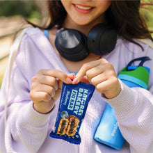 Person holding blueberry fig bar snack pack while wearing headphones