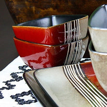 Red and beige stoneware bowls and plates with glossy black stripe bands