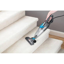 BISSELL handheld vacuum with floor brush attachment, cleaning a sofa seat