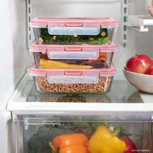 Clear glass refrigerator storage containers with red snap lids, stacked with groceries