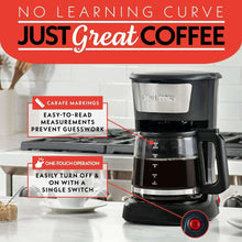 Black coffee maker with top reservoir and visible measurement markings on carafe