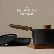 Black nonstick pot and pan set with wooden handles, stacked with lids