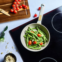 Taupe speckled non-stick fry pan with gold handle filled with green beans