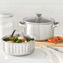 Stainless steel steamer pot with glass lid and perforated steaming basket.