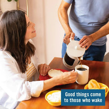 Person pouring hot coffee from a mug into another cup at breakfast table