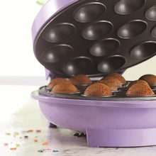 Open electric cake pop maker showing dark nonstick cavities and cake pops