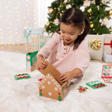 Child placing a wooden gingerbread house piece onto the house body