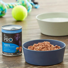 Wet dog food can with Puppy Pro+ label next to bowl of brown wet dog food