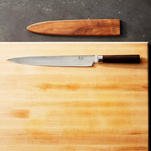 Slicer knife with stamped steel blade and dark handle on a cutting board