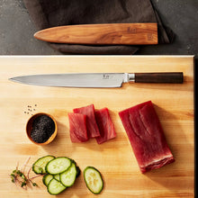 Slicer knife with stamped steel blade and dark handle on a wooden board with fish