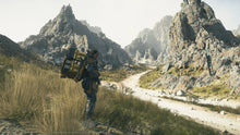 PS5 video game scene: character with cargo backpack walking along a winding desert road
