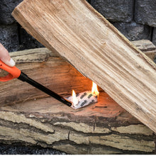 Fire starter cube lighting on split firewood in outdoor fire pit