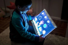 Kid holding an LED tracing board with blue glowing artwork