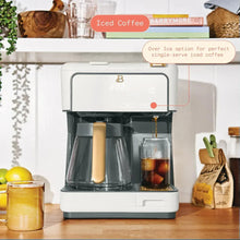 White coffee maker dispensing into glass cup for iced coffee