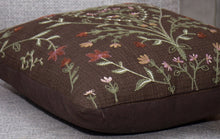 Brown embroidered throw pillow close-up with multicolor floral vine stitch detail