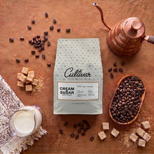Cultivar Cream & Sugar dark roast coffee bag with whole beans and sugar cubes.