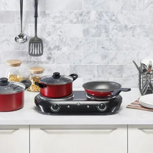 Black double-burner electric cooktop with pots and a pan on two coil heating plates