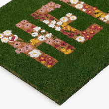 Outdoor coir doormat, green surface with floral “HELLO” lettering in blocks