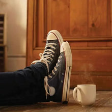 Coffee mug on the floor near dark sneakers, with brewed coffee visible.